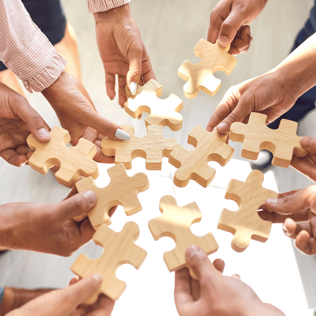 People holding jigsaw puzzle pieces in a circle