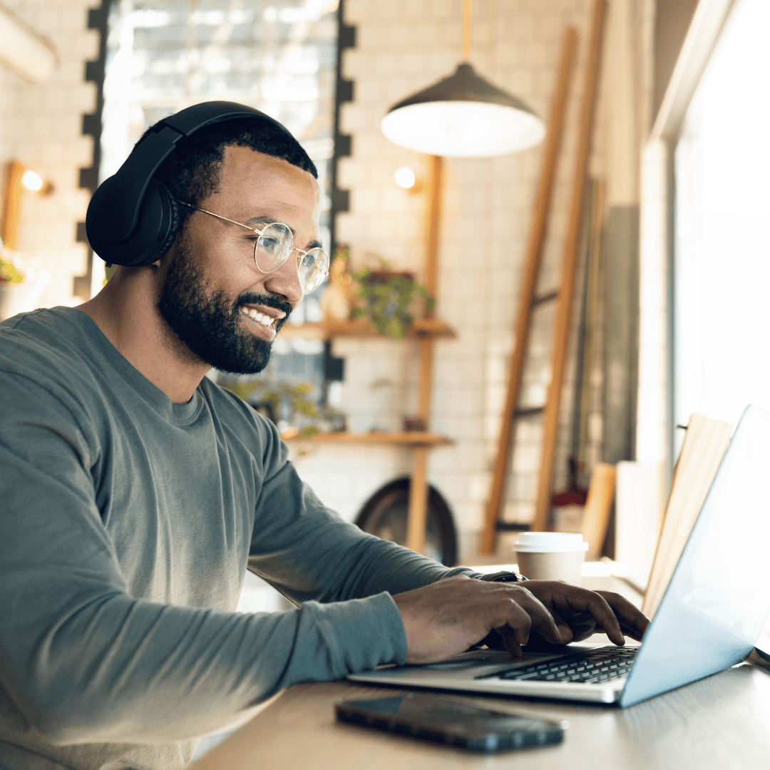 Copywriter sat typing on a laptop wearing headphones