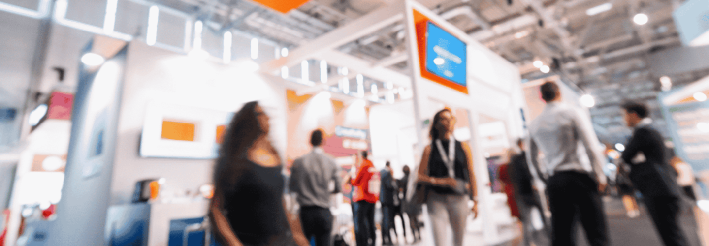 multiple people walking around at a trade show with exhibition stands